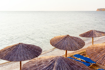 Morning light over umbrellas with loungers, chaise are placed next to the coastline, along water...