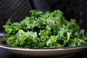 Fresh green curly kale leaves on black board, isolated. Healthy food. 