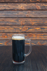 Close-up of a glass of dark beer on a wooden table. wooden background