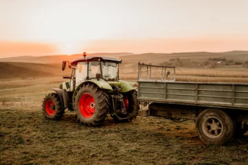 Foto op Aluminium industrial machinery. Harvesting details with tractor and trailer transporting harvest at sunset © aboutmomentsimages