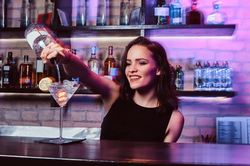 A beautiful girl bartender prepares an alcoholic cocktail with vodka