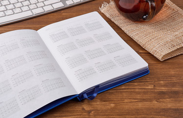 Top view of open pocket calendar or personal organizer on rustic wooden table with laptop and succulent plant