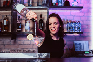 A beautiful girl bartender prepares an alcoholic cocktail with vodka