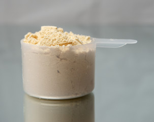 Pot of Whey Protein. Pouring whey protein into the pot with the scoop. Pouring white powder into the recipient  background.