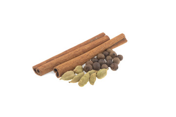 two cinnamon sticks, cardamom and allspice isolated on white background