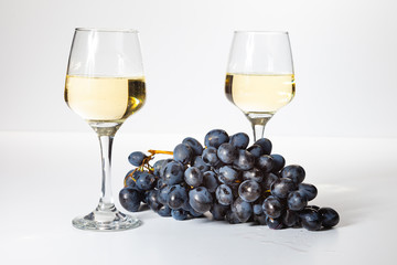 A glass of white wine. Bunch of grapes on a white background.