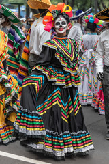 Fototapeta na wymiar Colorful participants in the festival of the Day of the dead in Mexico. Attractive skull costumes worn by dancing Mexican girls