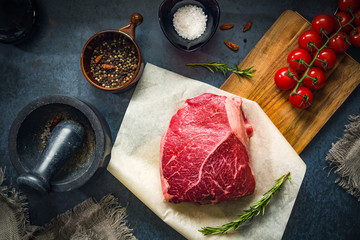 Raw Fresh Marbled Meat Beef with spices ready for cooking on a blue concrete background top view.