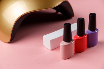 UV lamp lights for nails and set of cosmetic tools for manicure and pedicure on pastel background. Minimal creative concept. Pink background in pastel colours