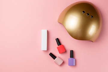 UV lamp lights for nails and set of cosmetic tools for manicure and pedicure on pink background. Top view. Flat lay. Copy space. Minimal creative concept. Pink background in pastel colours