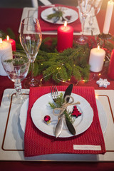 Table served for Christmas dinner, festive setting with decorations, burning candles and fir-tree branches