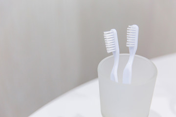 Fototapeta na wymiar White toothbrushes in a glass in the bathroom. Two toothbrushes. Toothbrush