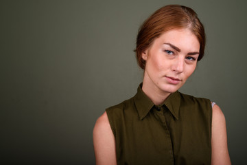 Young woman wearing green sleeveless top against colored backgro
