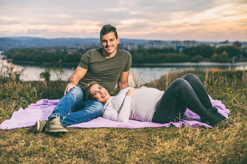 Naklejka na ściany i meble Husband and his pregnant wife enjoy spending time together outdoor.