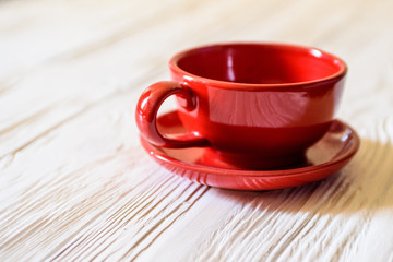 Obraz premium a red mug with a saucer on a white wooden background.