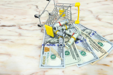Business, finance and economy concept. Dollar and shopping cart on marble tile background with copy space. Selective focus, view from top.