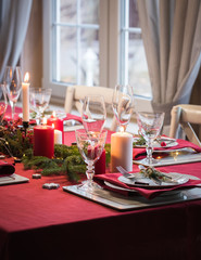 Table served for Christmas dinner, festive setting with decorations, burning candles and fir-tree branches