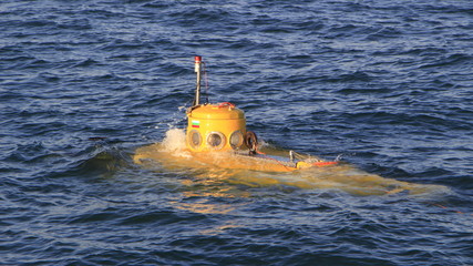 A shot of a small yellow submarine is resurfacing