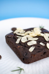 Chocolate Brownie with almond slice in white plate.
