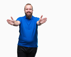 Young caucasian hipster man wearing blue shirt over isolated background looking at the camera smiling with open arms for hug. Cheerful expression embracing happiness.