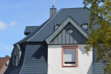 Dachgauben in Stehfalz-Zinkblechverkleidung am Ziegeldach eines Wohngebäudes Regenrinne und Regenfallrohr