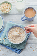 Oatmeal porridge bowl on the white wooden background.