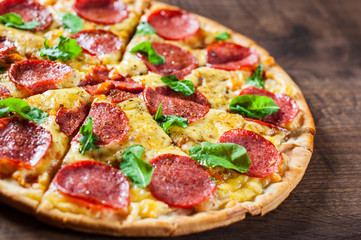 Pepperoni Pizza with Mozzarella cheese, salami, Tomato sauce, pepper, Spices and Fresh Basil. Italian pizza on wooden table background
