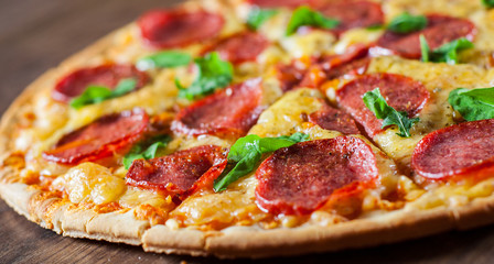 Pepperoni Pizza with Mozzarella cheese, salami, Tomato sauce, pepper, Spices and Fresh Basil. Italian pizza on wooden table background