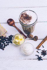 Bulletproof coffee. Ketogenic diet coffee with coconut oil and butter (ghee). Cup of bulletproof coffee and ingredients, paleo diet. On white wooden background