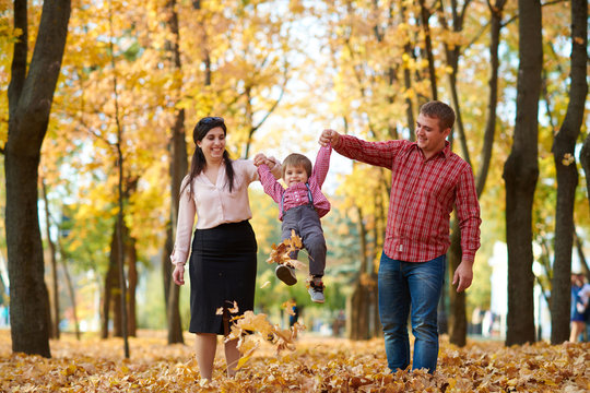 Parents And Child Are Walking In Autumn City Park. Bright Yellow Trees.