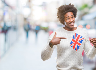 Afro american man flag of United Kingdom over isolated background very happy pointing with hand and finger