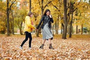Obraz premium Two happy girls running in autumn city park.