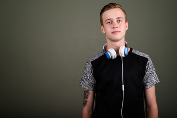 Young handsome man with blond hair wearing headphones against co