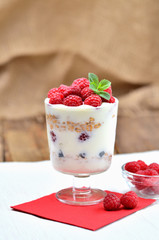 Greek yogurt with oatmeal and fresh raspberries in a glass - vertical photo