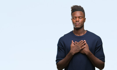 Fototapeta premium Young african american man over isolated background smiling with hands on chest with closed eyes and grateful gesture on face. Health concept.