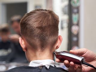 Barber making  haircut to  boy with clipper.