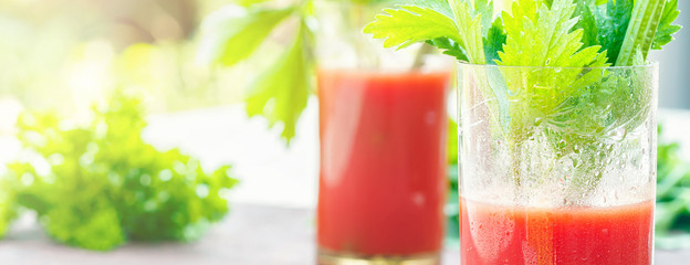 Two glasses of tomato juice homemade from garden organic vegetables decorated with twigs leaves of parsley and celery in table opposite green garden in sunset sunlight. - 234745976
