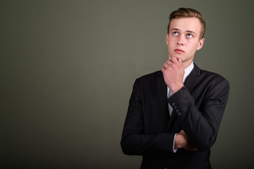 Young handsome businessman wearing suit against colored backgrou