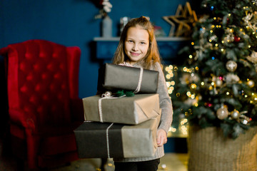 Little beautiful girl holds christmas gifts and happy from this