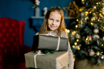 Little beautiful girl holds christmas gifts and happy from this