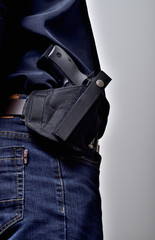 Textile holster with a pistol gun on the belt, blue jeans, a black shirt