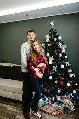 Pregnant mother and her husband at home with christmas decorations.