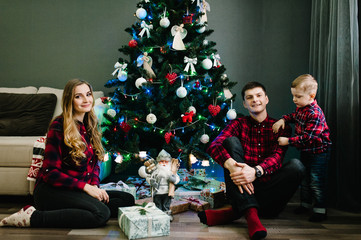 Christmas family give gift present box, Night Xmas. Merry Christmas and Happy Holidays! Family exchanging gifts. Parent and little children near Christmas tree indoors.