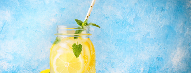 Coctail jar of lemonade and mint leaves on wooden table blue background Natural lemon water...