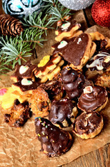 Christmas sweets with different types of candy on baking paper and Christmas decorations in background