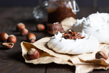 Portion of mini Pavlova meringue cake decorated with salted caramel sauce or chocolate paste over old brown wooden background.