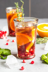 Cold lemonade or festive cocktail with pomegranate, mint and orange. Grey concrete background. Copy space.