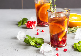 Cold lemonade or festive cocktail with pomegranate, mint and orange. Grey concrete background. Copy space.