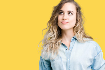 Beautiful young blonde woman over isolated background smiling looking side and staring away thinking.