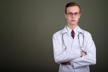 Young handsome man doctor against colored background